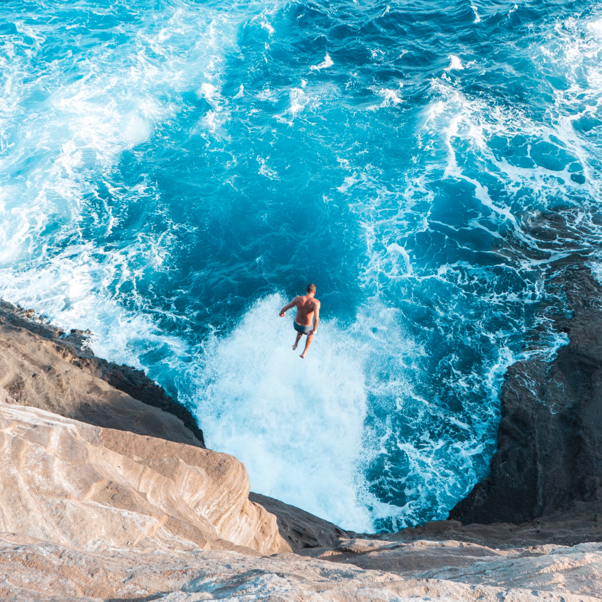 A man jumping off a cliff into the water